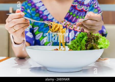 Hand hält Gabel und Löffel essen Spaghetti. Stockfoto