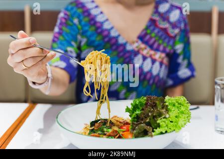 Hand hält Gabel essen Spaghetti im Restaurant. Stockfoto