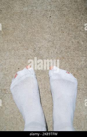 Mann Zehen stochen durch Löcher in weißen Socken, Härtekonzept Stockfoto