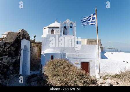 Kirche mit griechischer Flagge in Pyrgos, der alten Hauptstadt von Santorin, einer griechischen Kykladen-Insel in der Ägäis. Stockfoto