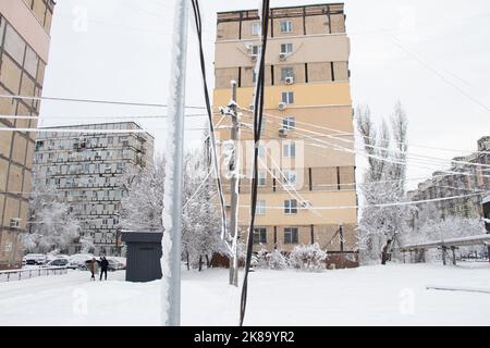 Elektrische Drähte im Schnee mit Eis an einem Pol in einem Wohngebiet der Stadt, durchhängende Drähte von der Schwere des Schnees in der Stadt Dnipro in Ukra Stockfoto