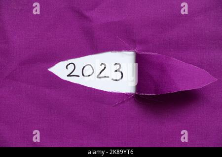 2023 geschrieben auf Papier auf zerrissenen Stoff, glückliches neues Jahr 2023 Stockfoto