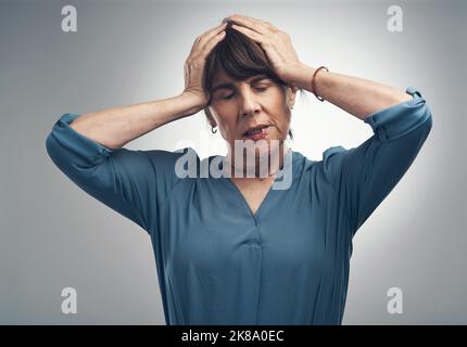 Das ist alles meine Schuld. Studioaufnahme einer älteren Frau, die gestresst vor grauem Hintergrund aussieht. Stockfoto