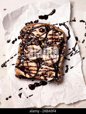 Toast mit Schokolade und Banane auf einem Stück weißem Papier. Stockfoto