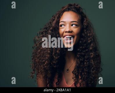 Hübsch und verspielt. Eine attraktive und schrullige junge Frau, die vor grünem Hintergrund im Studio posiert. Stockfoto