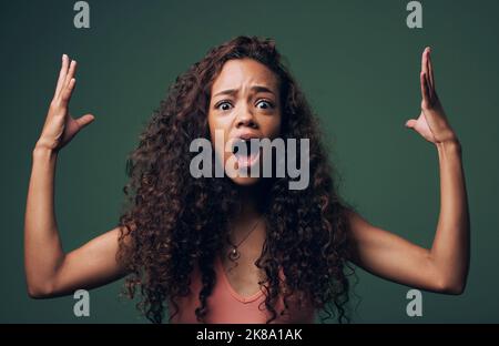 Achtung. Geblasen.Cropped Portrait einer attraktiven und skurrilen jungen Frau, die vor grünem Hintergrund im Studio posiert. Stockfoto