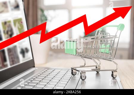 Inflation und Wirtschaftskrise. Roter Pfeil auf Karte, Einkaufswagen und Laptop. Hohe Inflationsrate. Online-Shopping- und Lieferservice-Konzept. Inflat Stockfoto