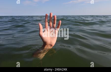 Die Hand der Person mit fünf Fingern in der Mitte des Meeres, die im Begriff ist, zu ertrinken Stockfoto