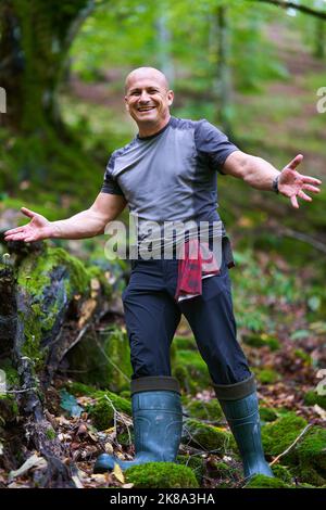 Erfahrener Wanderer, der sich auf einem Wanderweg durch einen alten, üppigen Wald schlenderte Stockfoto