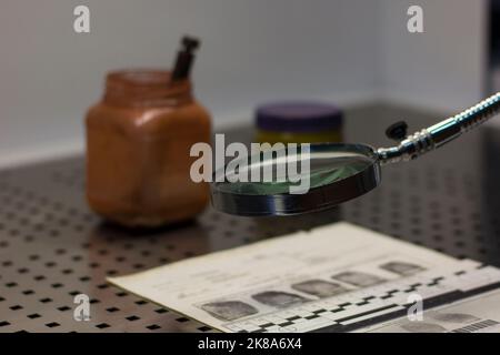 Forensisches Lineal, Lupe, Fingerabdruckkarte und ein Glas Magnetpulver im Hintergrund Stockfoto