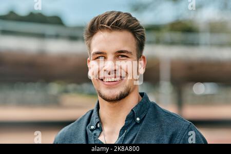 Jeder Erfolg beginnt mit der Entscheidung, es zu versuchen. Zugeschnittenes Porträt eines hübschen jungen Studenten draußen auf dem Campus. Stockfoto