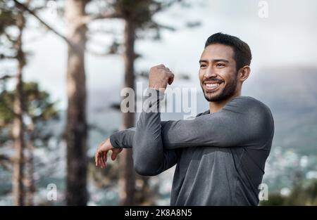 Erwärmen meines Körpers für meinen Lauf. Ein hübscher junger Mann, der sich vor dem Training im Freien allein dehnt. Stockfoto