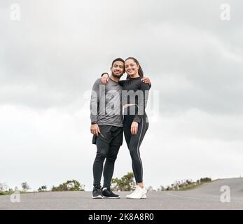 Freunde treiben dich dazu, besser zu sein. In voller Länge Porträt zweier junger Sportler, die nach ihrem morgendlichen Lauf im Freien mit ihren Armen umeinander stehen. Stockfoto