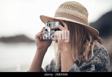 Ich kann mir keinen besseren Weg vorstellen, meine Zeit zu verbringen. Eine junge Frau mit ihrer Kamera am Strand. Stockfoto