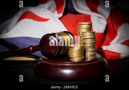 Stapel goldener Münzen mit Richter-Gavel und Union Jack im Hintergrund. Stockfoto