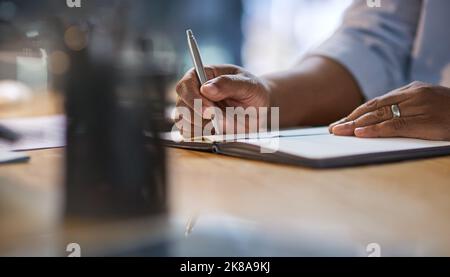 Wünschen Sie sich kein anderes Leben, arbeiten Sie dafür. Ein nicht erkennbarer Geschäftsmann, der nachts allein an seinem Schreibtisch sitzt und in einem Notizbuch schreibt. Stockfoto