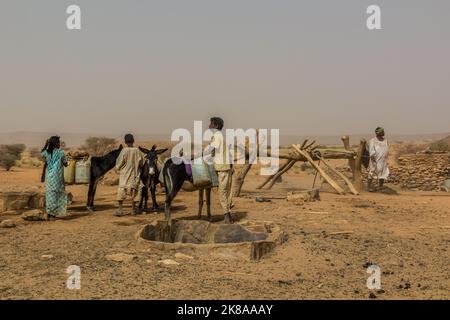 BUNDESSTAAT AM NIL, SUDAN - 5. MÄRZ 2019: Dorfbewohner an einem Brunnen in einer trockenen Region des Sudan. Stockfoto