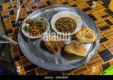 Traditionelles Gericht im Sudan - Fuul (Eintopf gekochter Fava-Bohnen), Salat und Brot. Stockfoto