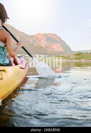 Frau, die im Sommerurlaub oder auf Reisen ein Kajak oder Boot auf einem Fluss oder See rudert. Touristen erkunden die Natur auf dem Wasser während eines tropischen Abenteuers Stockfoto