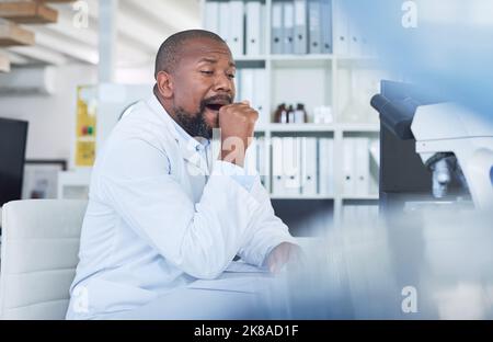 Zu viel Wissenschaft, zu wenig Schlaf. Ein Wissenschaftler, der müde aussieht, während er in einem Labor forscht. Stockfoto