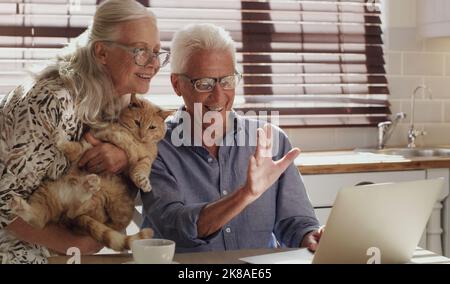 Es ist so schön, alle zu sehen. Glückliches Seniorenpaar mit einem Laptop für einen Video-Chat zu Hause. Stockfoto