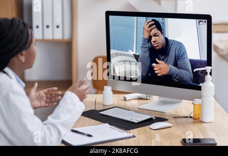 Ein junger Mann, der einen Videoanruf mit einem Arzt auf einem Computer hat, spricht mit einem Spezialisten, um seine Schmerzen zu lindern. Stockfoto