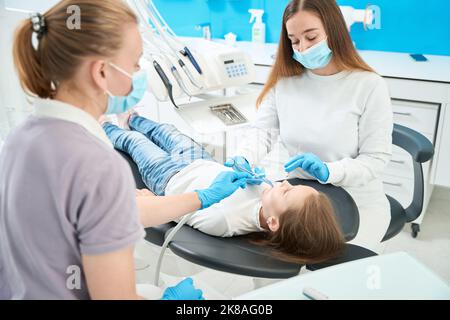 Konzentrierter pädiatrischer Zahnarzt, der dem Patienten Anästhesie verabreichte Stockfoto