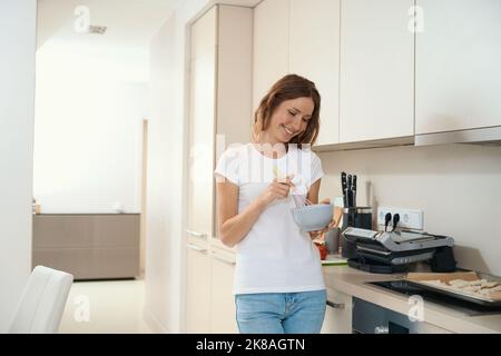 Frau schlägt leer für ein Gericht auf einem tiefen Teller Stockfoto