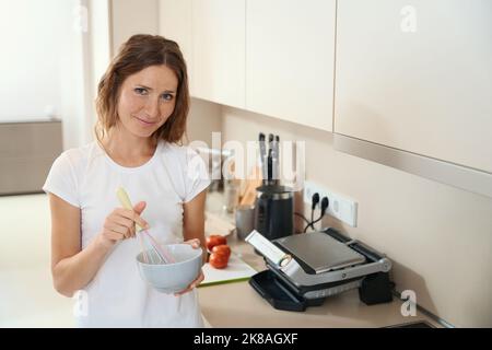 Frau mischt Zutaten zum Kochen in einer tiefen Schüssel Stockfoto