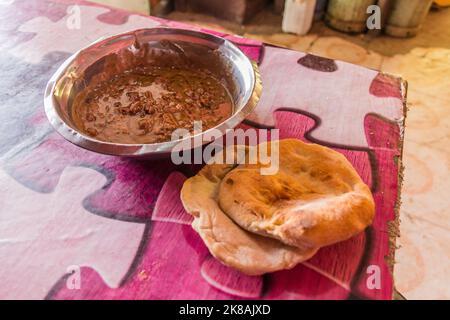 Traditionelles Gericht im Sudan - Fuul (Eintopf gekochter Fava-Bohnen) und Brot. Stockfoto