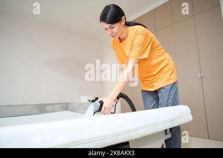 Weibliche Durchführung der allgemeinen Reinigung der Schlafmatratze Stockfoto