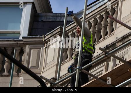 Westminster, London, Großbritannien. 22. Oktober 2022. Am 22. Oktober wird in London ein großer marsch und eine Kundgebung stattfinden, um Großbritannien zum EU-Beitritt aufzufordern. Die Teilnehmer treffen sich um 12:00 Uhr in der Nähe des Dorchester Hotels in der Park Lane, bevor sie zu einer Kundgebung zum Parliament Square gehen. Die marschroute umfasst Piccadilly, Saint James' Street, Pall Mall, Cockspur Street und Whitehall. Ein Baumeister auf Gerüsten, der auf vorbeifahrende Demonstranten gestikuliert. Foto: Paul Lawrenson/Alamy Live News Stockfoto