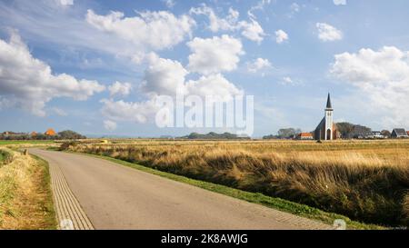 Panorama der flachen Landschaft von Texel mit der kleinen Kirche des kleinen Dorfes Den Hoorn. Stockfoto