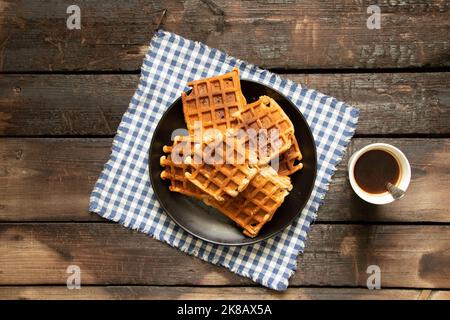 Wiener Waffel auf einem Holztisch und eine Tasse Kaffee, Waffeln zum Frühstück in der Küche zu Hause Stockfoto