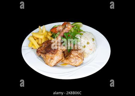 Gegrillte Hähnchenkoteletts mit Reis, Salat und pommes Frites auf einem weißen Teller auf schwarzem Hintergrund Stockfoto