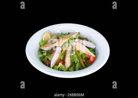 Hähnchen Caesar Salat auf einem weißen Teller auf schwarzem Hintergrund Stockfoto