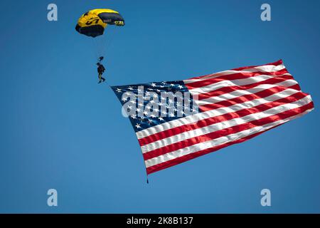 Ein Mitglied des Fallschirmsprungteams der US Navy Leap Frogs bringt die amerikanische Flagge zur Miramar Airshow 2022 in San Diego, Kalifornien. Stockfoto