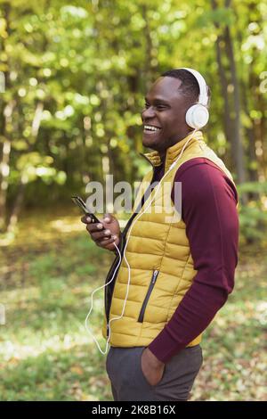 Afroamerikanischer Mann hört Musik im Frühlingspark. Gadget-, App- und Streaming-Service-Konzept Stockfoto