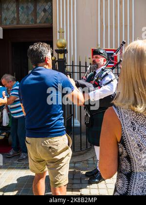 Die schottische Piper beklagt sich, als die Menschen aus einer Trauermesse für Königin Elizabeth 2 in der Kathedrale auf dem Felsen von Gibraltar aussteigen Stockfoto