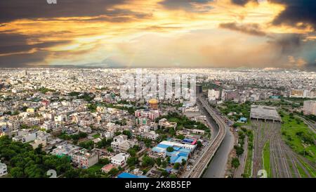 Stabile Antenne getan Aufnahme Blick auf Regenbogen über überfüllten Häusern Häuser Gebäude von jaipur mit dunklen Monsun Wolken über und Verkehrsfahrzeuge und Stockfoto