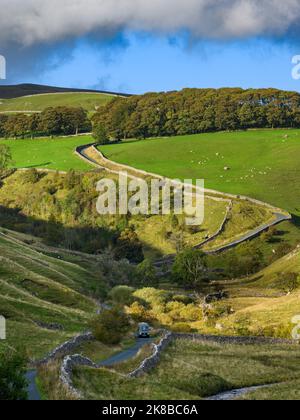 1 Van auf einer ruhigen gewellten Landstraße (malerische, sonnendurchflutete, hügelige Landschaft, steiler Aufstieg, Bach) - in der Nähe von Kettlewell, Yorkshire Dales, England. Stockfoto