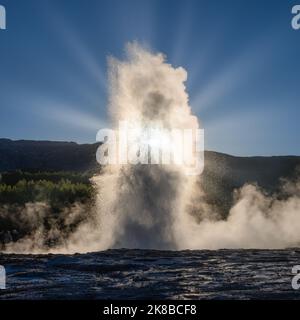 Strokkur Geyser Island, Abend mit Sonnenstrahlen, die durch die Wassersäule scheinen Stockfoto