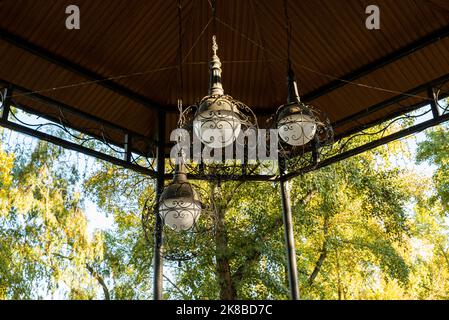 LED-Laterne zur Straßenbeleuchtung. Moderne Straßenlampe auf einem Metallmast neben einem grünen Baum gegen den blauen Himmel bei strahlendem Sonnenschein. Moderne LED-Lampe Stockfoto