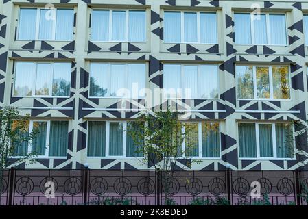 Fassade eines weißen Gebäudes mit vielen weißen Fenstern. Hausfassade eines alten historischen Gebäudes mit weißen Wänden. Außendesign des Apartmentgebäudes wi Stockfoto