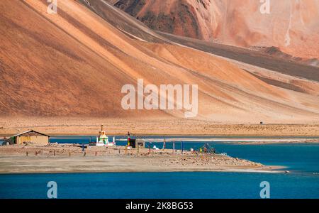 Buddhistische Stupa am Pangong Lake, der höchste Salzwassersee der Welt, ist blau gefärbt und steht in krassem Kontrast zu den kargen Bergen, die ihn umgeben. Stockfoto