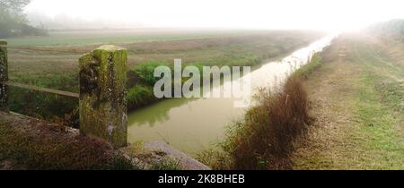 Eine alte Brücke, ein Kanal und viel Nebel Stockfoto