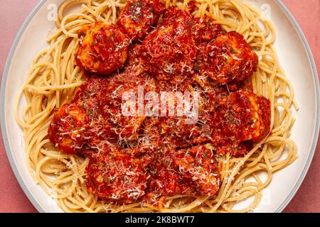 Putenfleischbällchen mit Knoblauch- und Basilikumtomatensauce und Vollkornteigwaren, die von oben mit Parmesan bestreut wurden Stockfoto