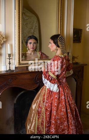 Schöne Frau in Renaissance-Kleid Blick in einen antiken goldenen Spiegel in ihrem Schloss Stockfoto