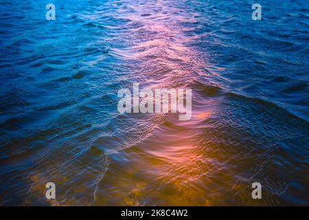 Abstrakter Wasserhintergrund. Wasseroberfläche und Sonnenreflexion. Wunderschöne Farben in Blau, Türkis, Orange und Pink Stockfoto