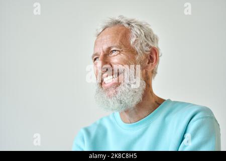 Lachender bärtiger älterer Mann isoliert, der an einer weißen Wand stand. Stockfoto